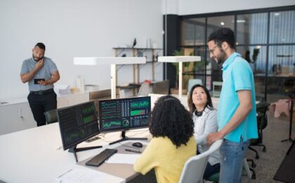 Office employees collaborate on financial data at modern workspace, engaging in teamwork and communication.