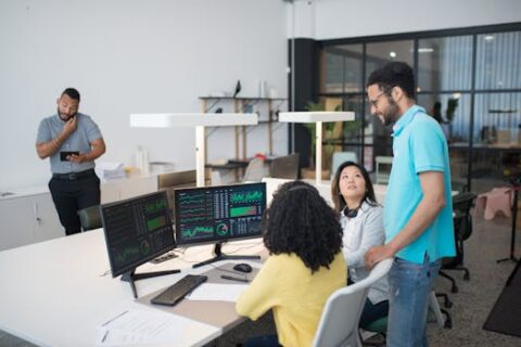 Office employees collaborate on financial data at modern workspace, engaging in teamwork and communication.